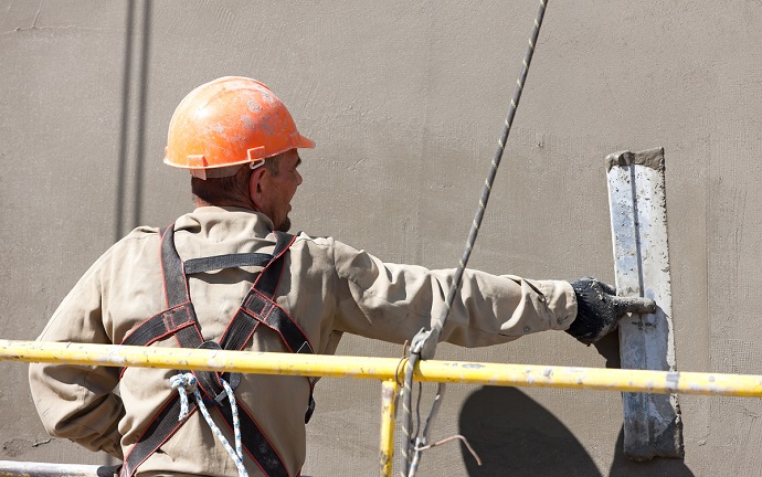 Nakladanie tynku przez pracownika budowlanego na elewacji budynku